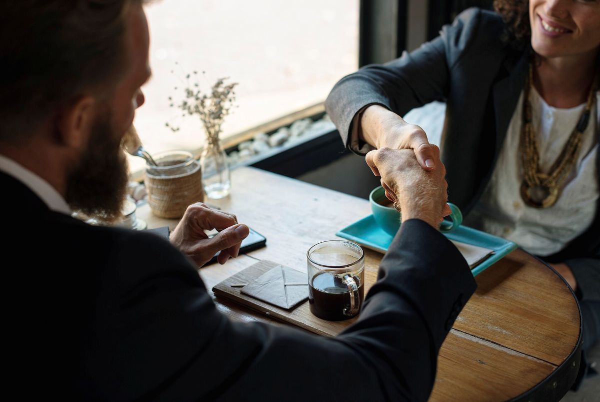 Hai người bắt tay bên bàn cà phê sau khi trao đổi hợp đồng